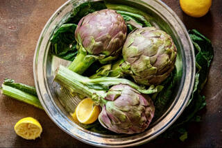 fresh artichokes in a bowl with lemon.