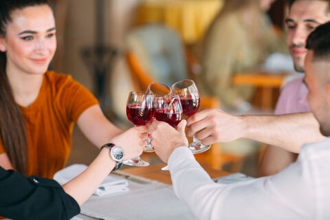 cheers with glass of red wine with four people