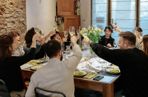 smiling group cheers with wine at dining table