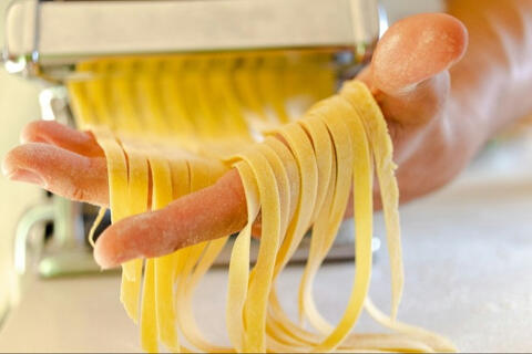 fresh tagliatelle being made with pasta machine