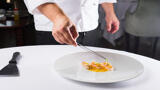 chef delicately decorates plate of food