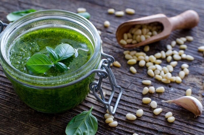 fresh basil pesto in a glass jar with pine nuts