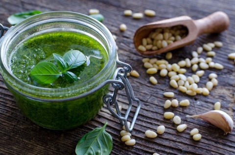 fresh basil pesto in a glass jar with pine nuts