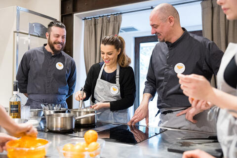 student stirring saucepan with chefs observing