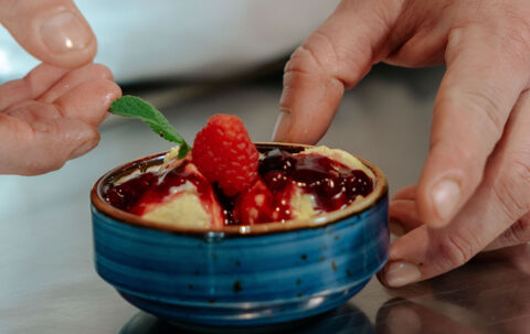 Chef serving cream gelato with raspberries