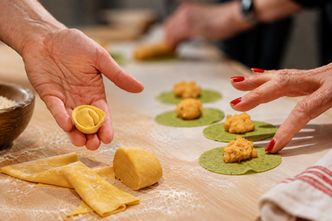 Hands making traditional Tuscan tortelli, with potato-filled pasta being shaped by hand.