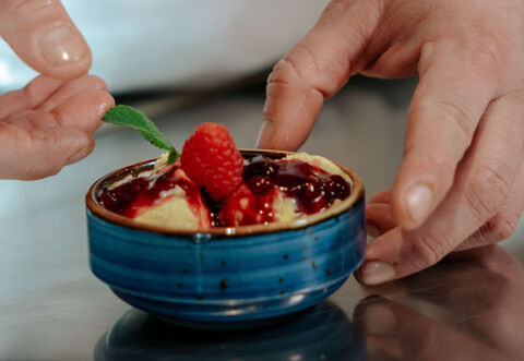 chef placing mint leaf on a bowl of gelato