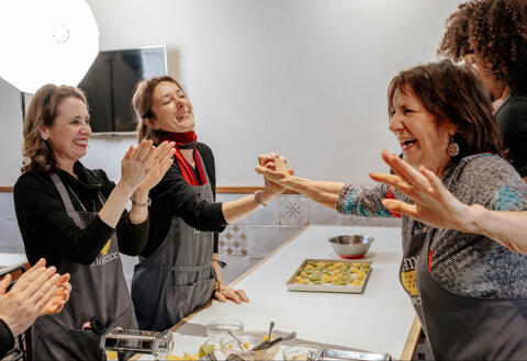 group of women smiling and laughing during cooking class