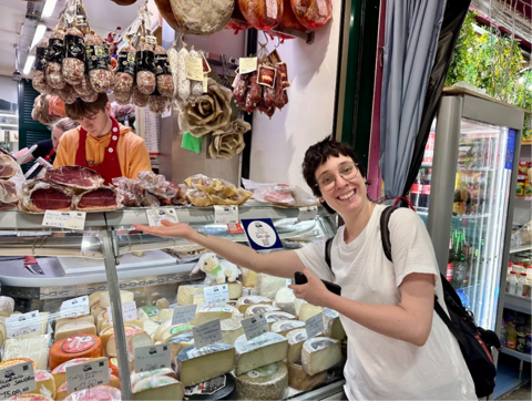 young woman posing in front of cheese and cured meat stand at florence central market