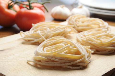 uncooked fresh spaghetti on a wooden board