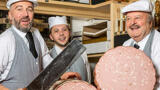 mortadella being sliced and displayed by three butchers