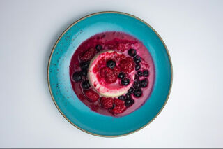 pana cotta with red berries on a blue plate