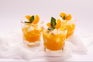 three orange parfait desserts served in glasses with mint