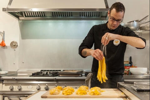 chef places fresh tagliatelle on wooden board