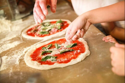 two people making pizza with tomato basil and cheese