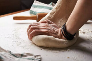 hands kneading pizza dough