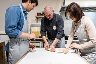 chef kneading pizza dough with students