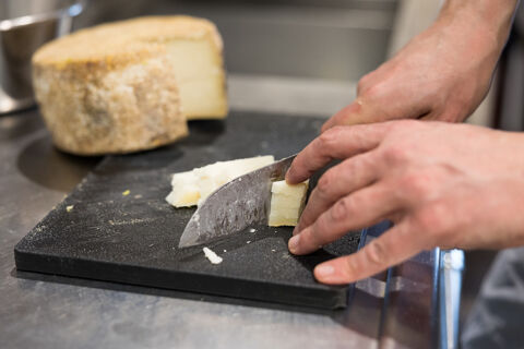 chef slicing pecorino cheese on a chopping board.
