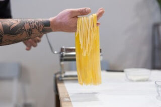 fresh tagliatelle pasta in chefs hands.