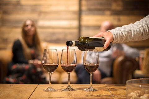 pouring red wine into three wine glasses