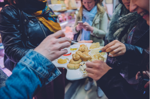 group of people sampling food items at outdoor market