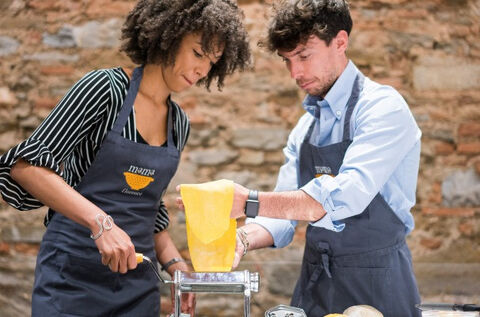 two people making fresh pasta with pasta machine