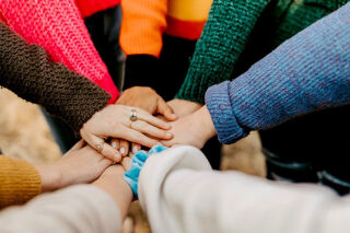 team of people with their hands laid one above the other