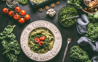 kale pasta served in a bowl with tomatoes.