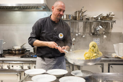 chef tossing tortelli in a sauce pan