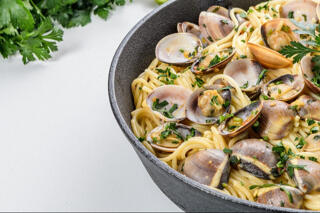 spaghetti with clams and parsley in saucepan