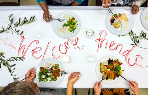 a dining table with plates of food and the words welcome friends written in red